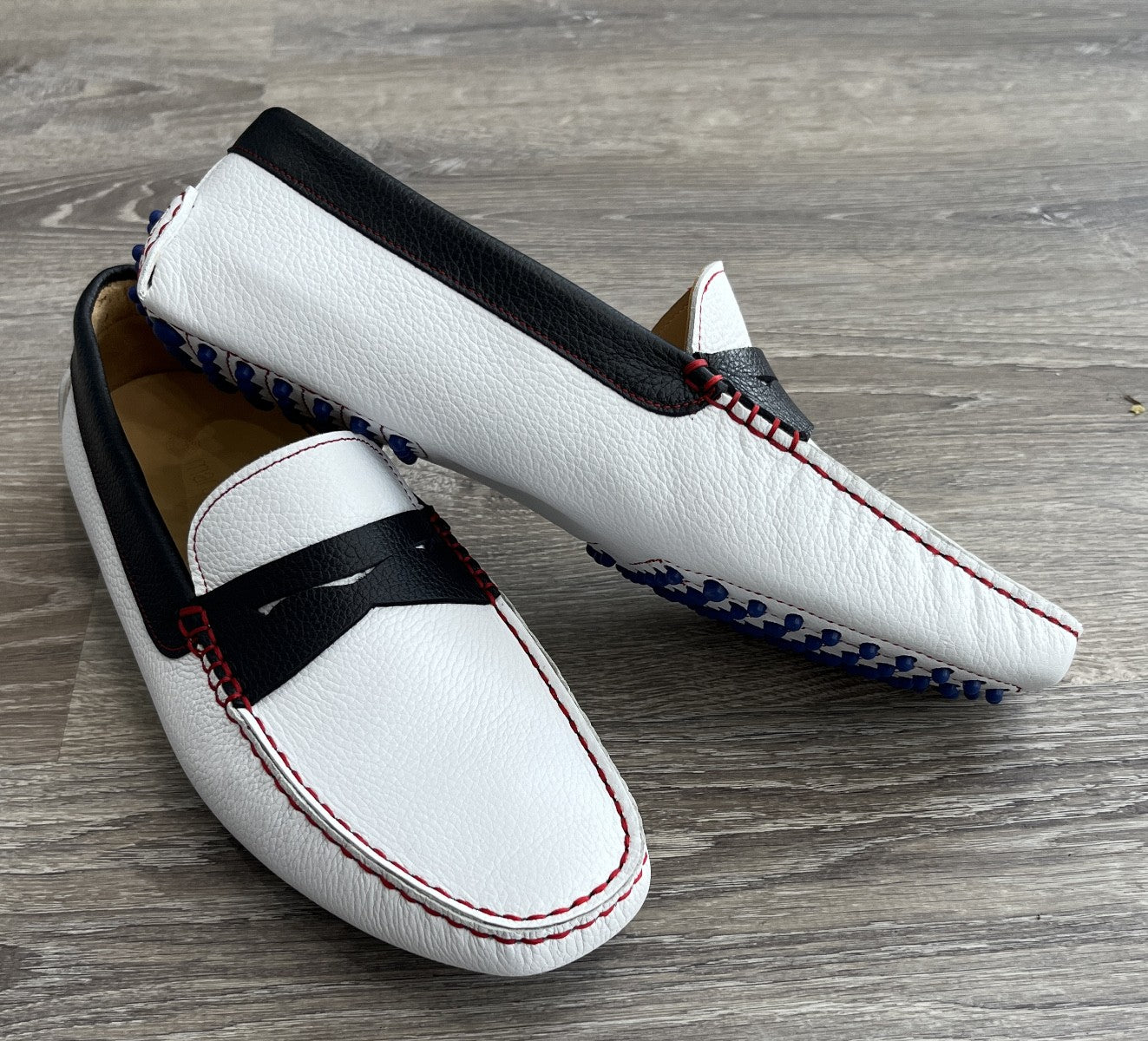 Choose this outstanding leather driver in fashionable white natural grain leather, accented with navy leather and cool red stitching. Featuring a royal blue gommini effect sole.   Soft foot bed for added comfort and a classic fit.  Designed and manufactured in Spain. By Marcello Sport