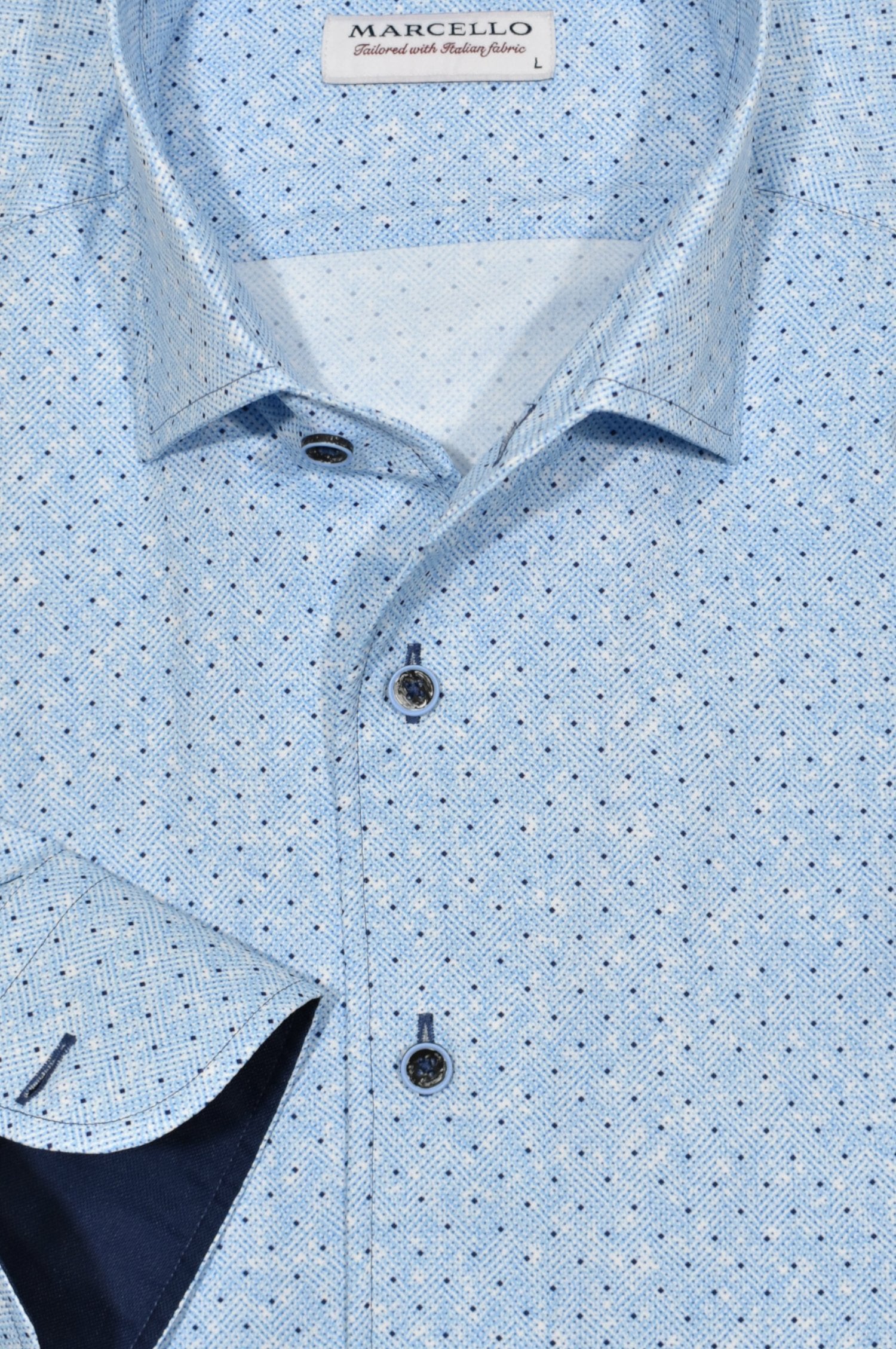 Elevate your style with the W932R Sky Dot Roll Collar. Featuring a Marcello exclusive one piece roll collar, this medium blue patterned herringbone shirt is accented with random navy dots. Exude confidence and sophistication with this must-have piece. By Marcello