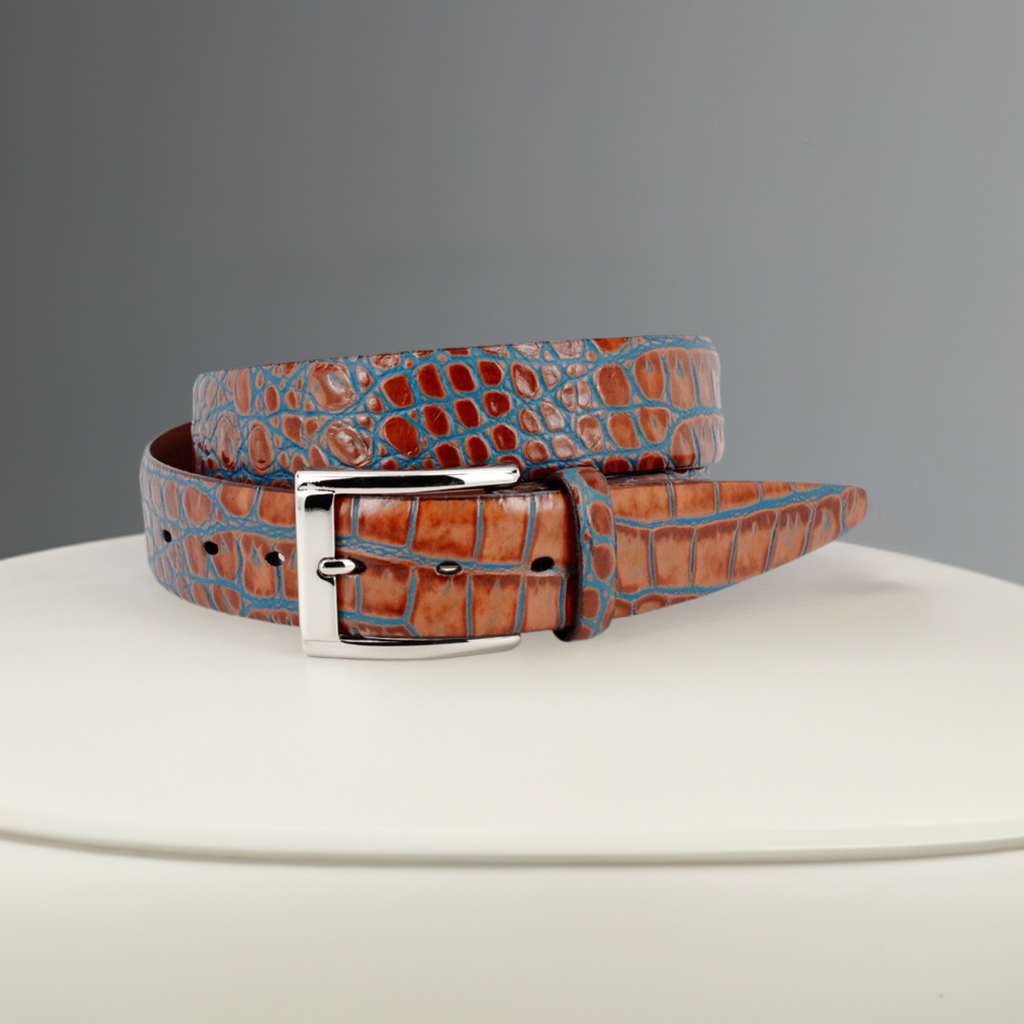 Crafted with impeccable attention to detail, the ZT52903 Italian Embossed Croc Cognac belt exudes sophistication and elegance. Crafted with soft Italian calf leather in a rich cognac hue, it has been stained with a teal blue technique for an unforgettable statement tone. Statement silver buckle and a 35mm or 1 7/16" width is the final nuance of this timeless accessory, perfect with any cool jeans. Assembled in the USA for a superior finish.