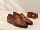 Magnanni Herrera Cuero brown woven leather loafers on pale limestone, with a coordinating brown leather belt behind them.